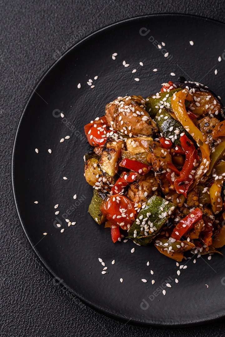 Prato asiático picante com filé de carne fatiado, pimenta, cenoura e sementes de gergelim sobre um fundo escuro de concreto