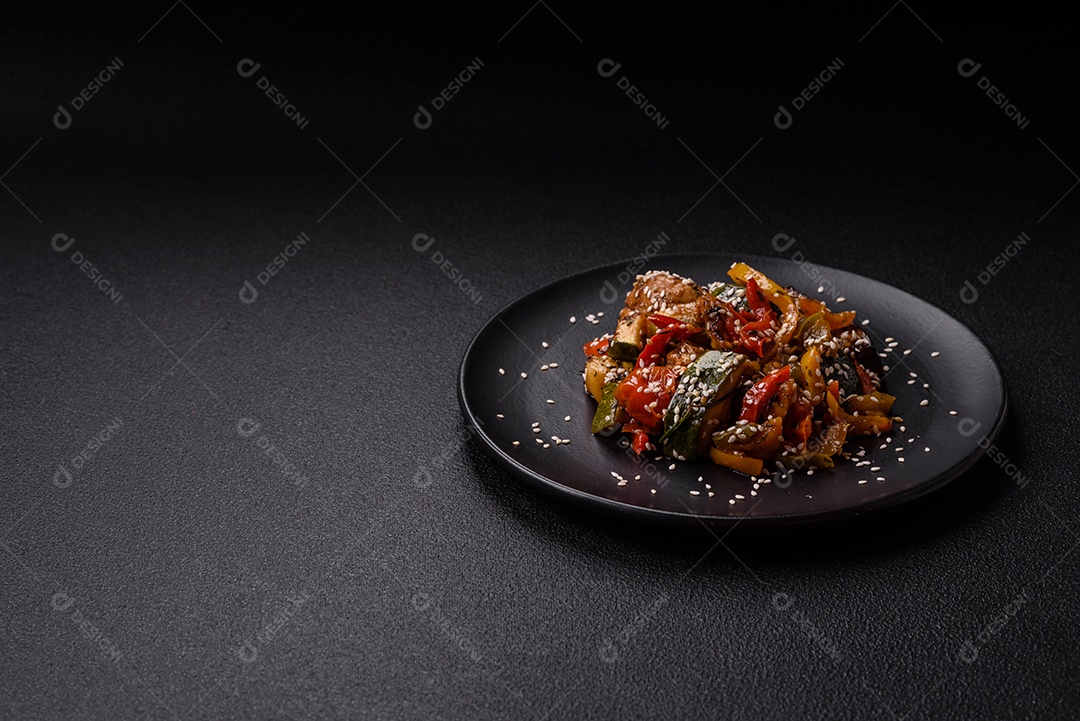 Prato asiático picante com filé de carne fatiado, pimenta, cenoura e sementes de gergelim sobre um fundo escuro de concreto