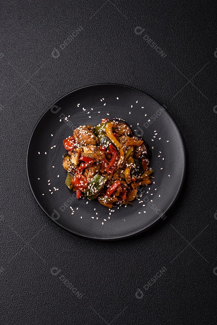 Prato asiático picante com filé de carne fatiado, pimenta, cenoura e sementes de gergelim sobre um fundo escuro de concreto