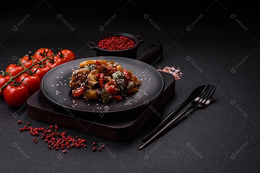 Prato asiático picante com filé de carne fatiado, pimenta, cenoura e sementes de gergelim sobre um fundo escuro de concreto