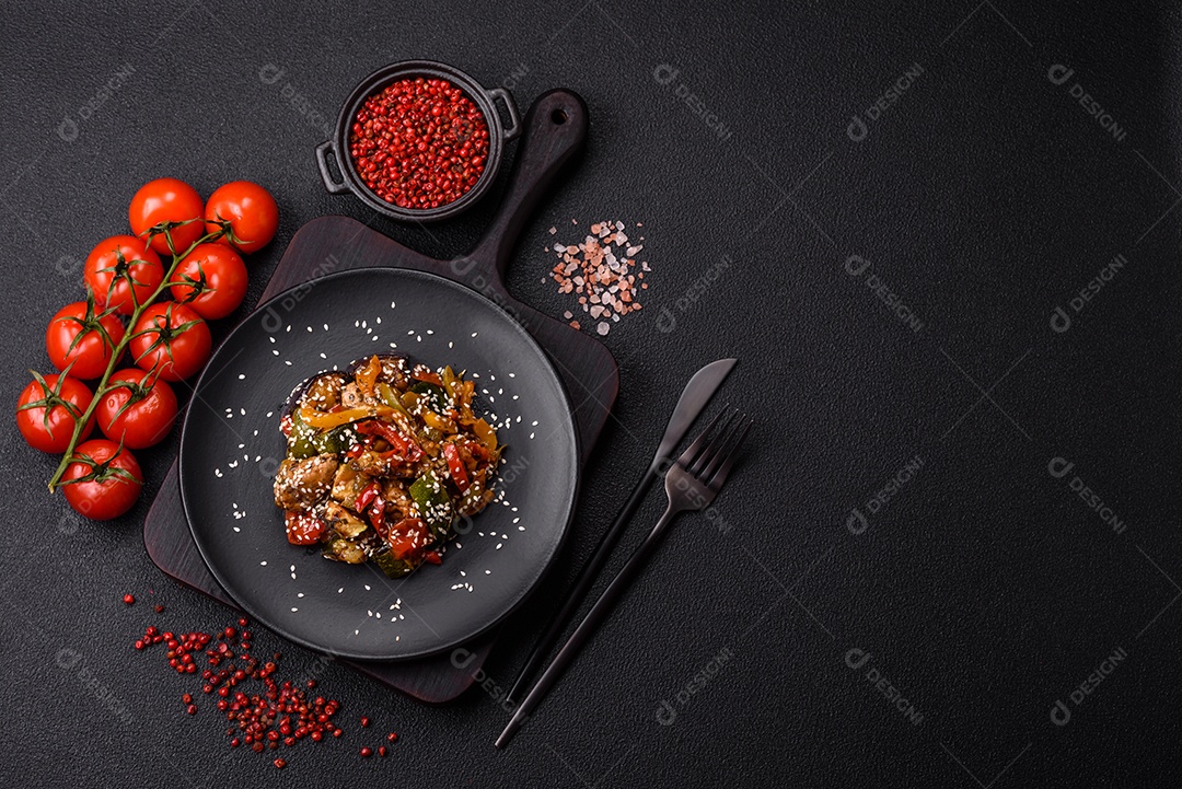 Prato asiático picante com filé de carne fatiado, pimenta, cenoura e sementes de gergelim sobre um fundo escuro de concreto