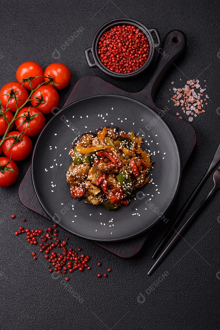 Prato asiático picante com filé de carne fatiado, pimenta, cenoura e sementes de gergelim sobre um fundo escuro de concreto