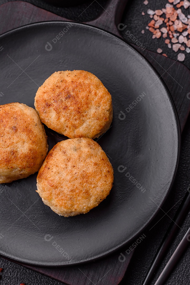 Deliciosas costeletas de peixe picado frito fresco com especiarias e ervas sobre um fundo escuro de concreto