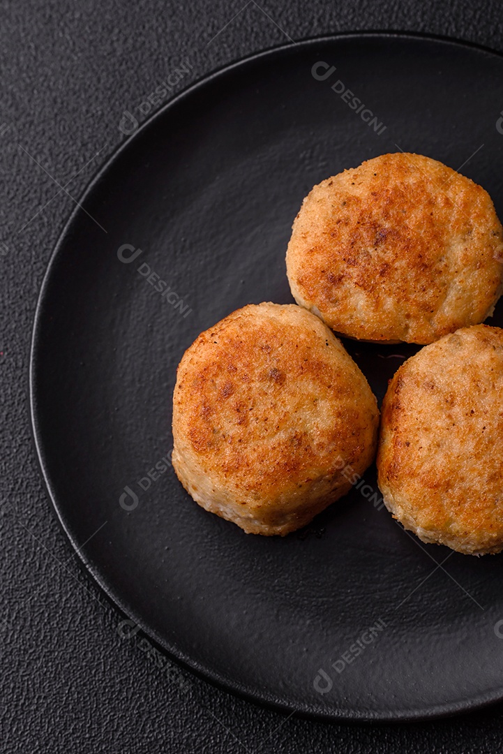 Deliciosas costeletas de peixe picado frito fresco com especiarias e ervas sobre um fundo escuro de concreto