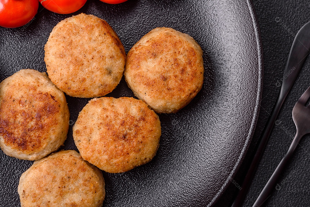 Deliciosas costeletas de peixe picado frito fresco com especiarias e ervas sobre um fundo escuro de concreto