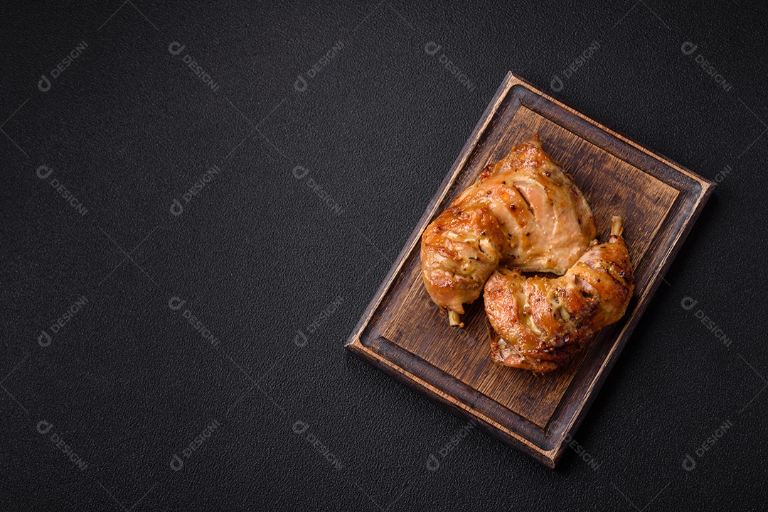 Deliciosa coxa ou quarto de frango grelhado com sal e especiarias em fundo escuro de concreto