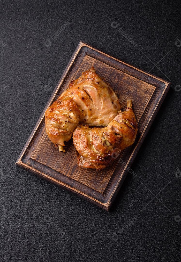 Deliciosa coxa ou quarto de frango grelhado com sal e especiarias em fundo escuro de concreto