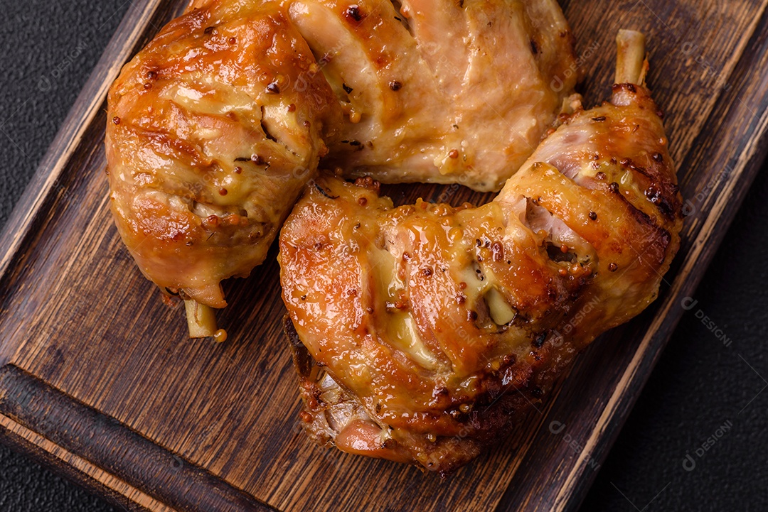 Deliciosa coxa ou quarto de frango grelhado com sal e especiarias em fundo escuro de concreto