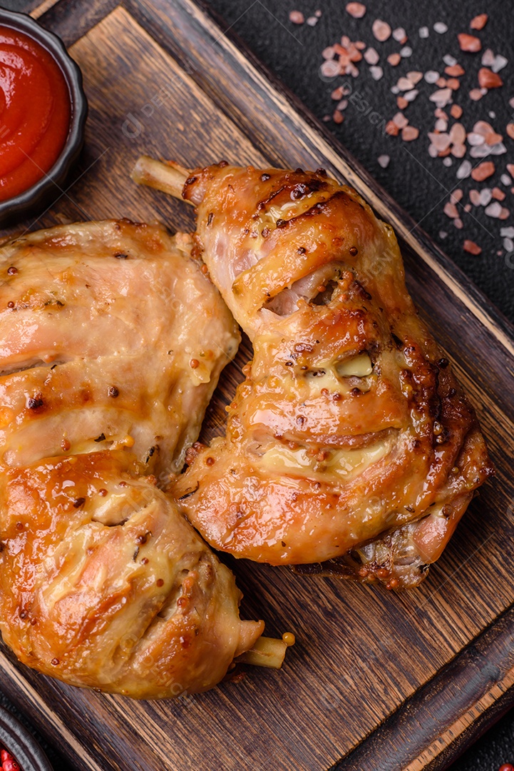 Deliciosa coxa ou quarto de frango grelhado com sal e especiarias em fundo escuro de concreto