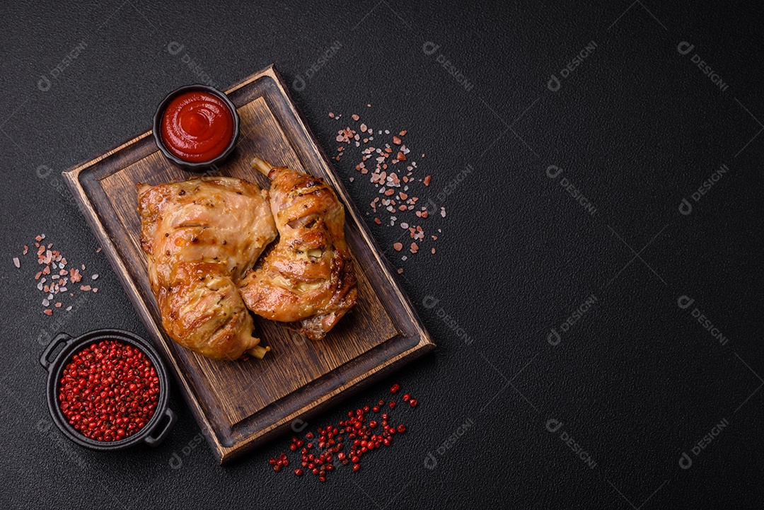 Deliciosa coxa ou quarto de frango grelhado com sal e especiarias em fundo escuro de concreto