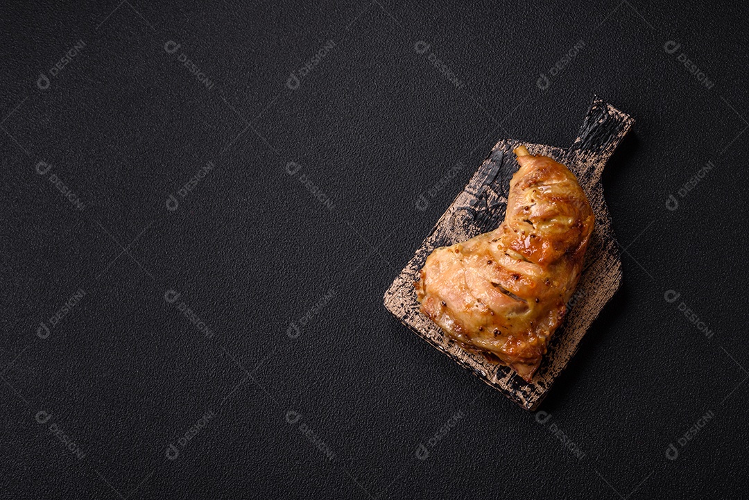 Deliciosa coxa ou quarto de frango grelhado com sal e especiarias em fundo escuro de concreto