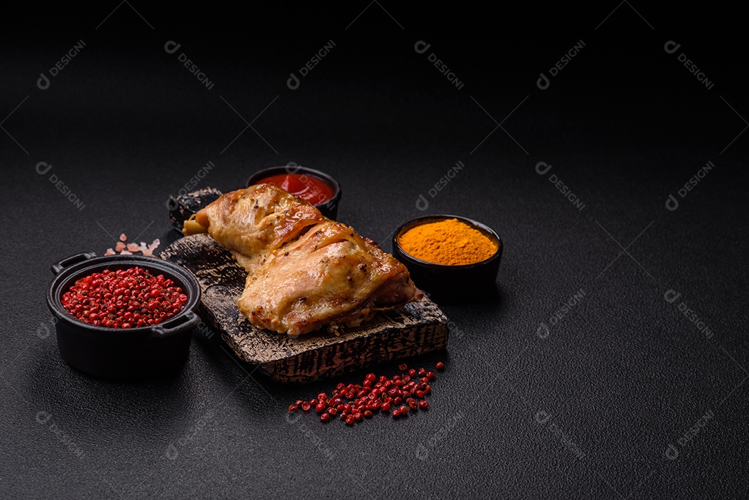 Deliciosa coxa ou quarto de frango grelhado com sal e especiarias em fundo escuro de concreto