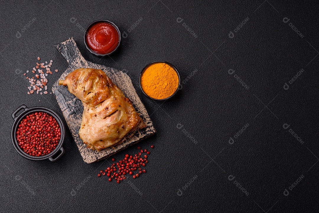 Deliciosa coxa ou quarto de frango grelhado com sal e especiarias em fundo escuro de concreto