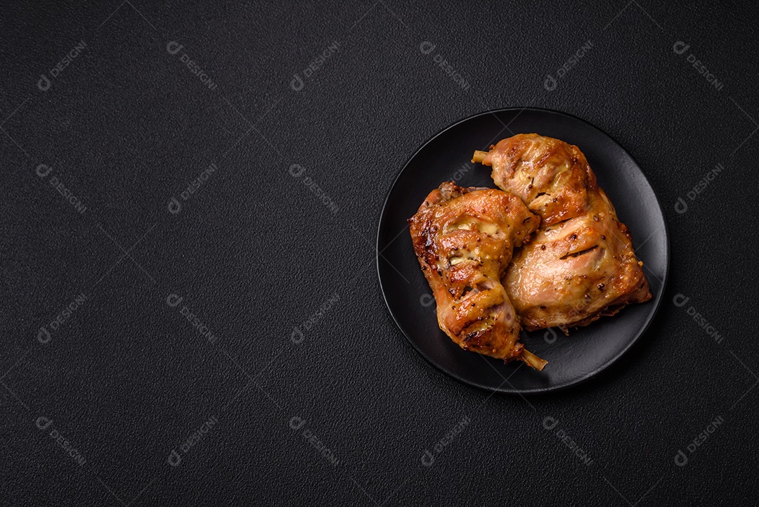 Deliciosa coxa ou quarto de frango grelhado com sal e especiarias em fundo escuro de concreto