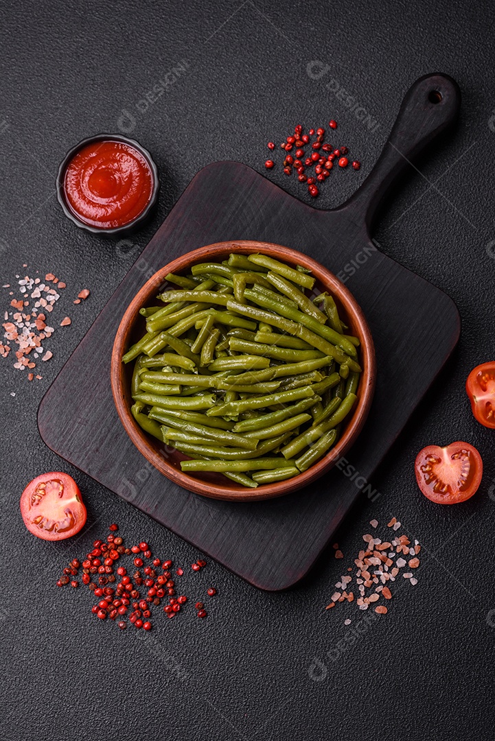 Vagens de feijão verde cozido com sal e especiarias sobre um fundo escuro de concreto