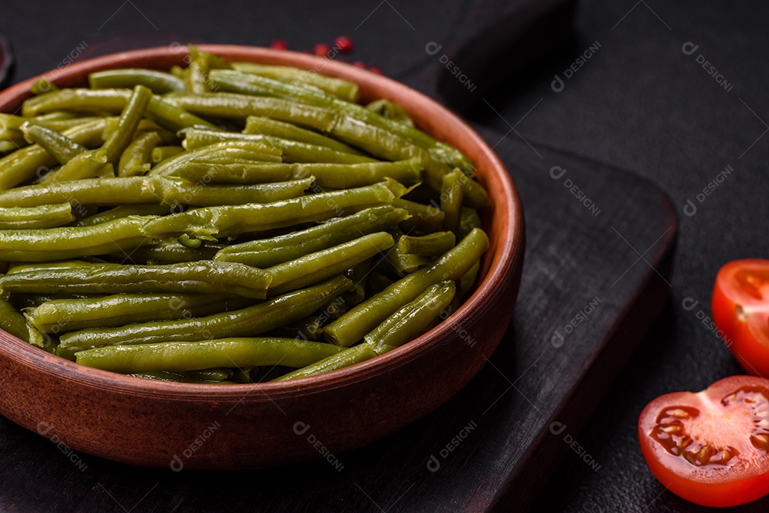 Vagens de feijão verde cozido com sal e especiarias sobre um fundo escuro de concreto