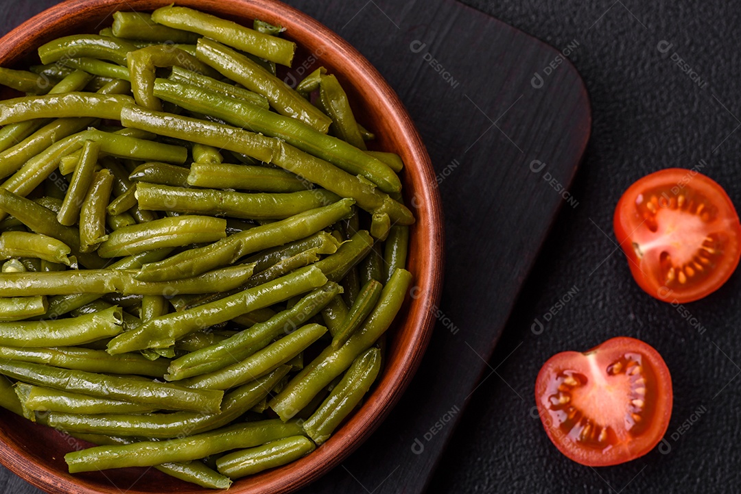 Vagens de feijão verde cozido com sal e especiarias sobre um fundo escuro de concreto