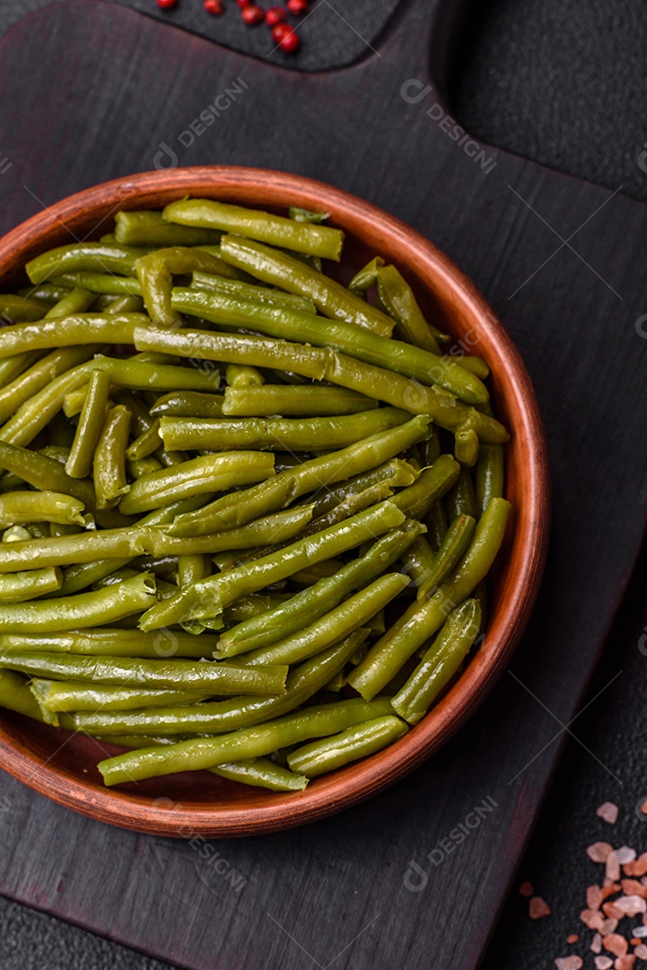 Vagens de feijão verde cozido com sal e especiarias sobre um fundo escuro de concreto