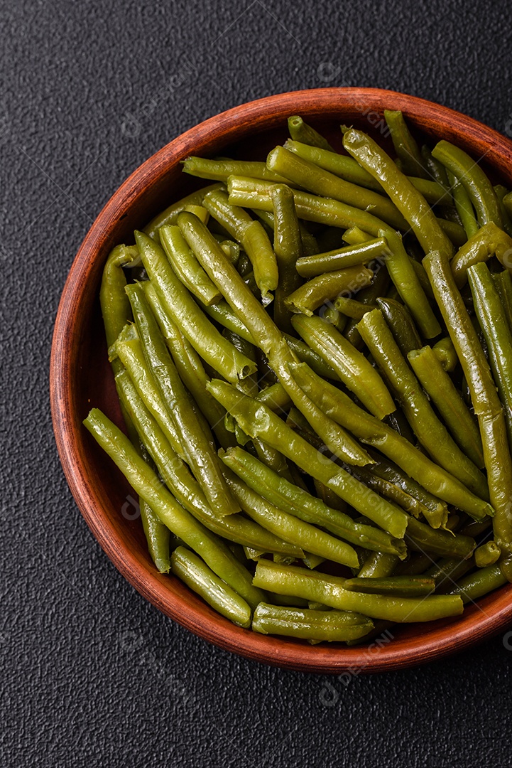 Vagens de feijão verde cozido com sal e especiarias sobre um fundo escuro de concreto