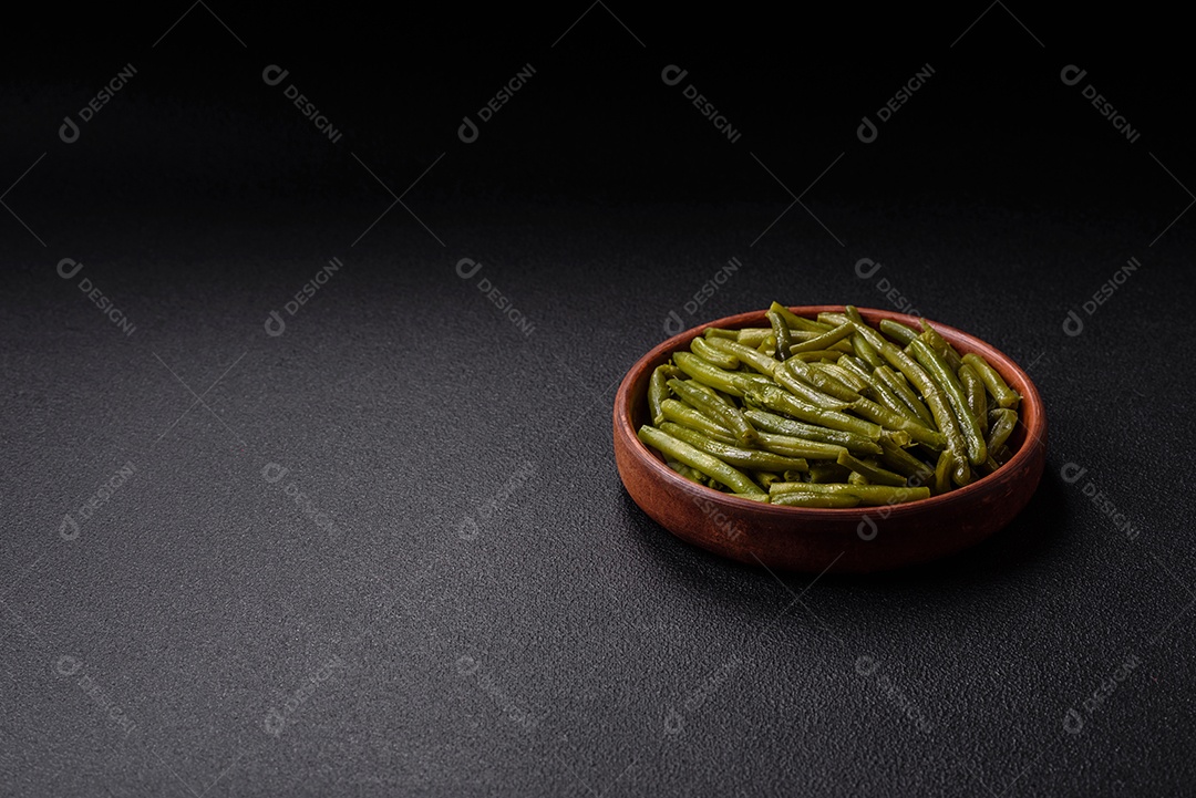 Vagens de feijão verde cozido com sal e especiarias sobre um fundo escuro de concreto