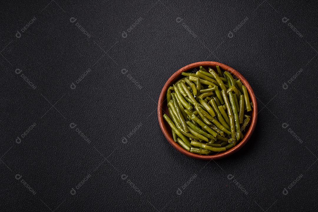 Vagens de feijão verde cozido com sal e especiarias sobre um fundo escuro de concreto