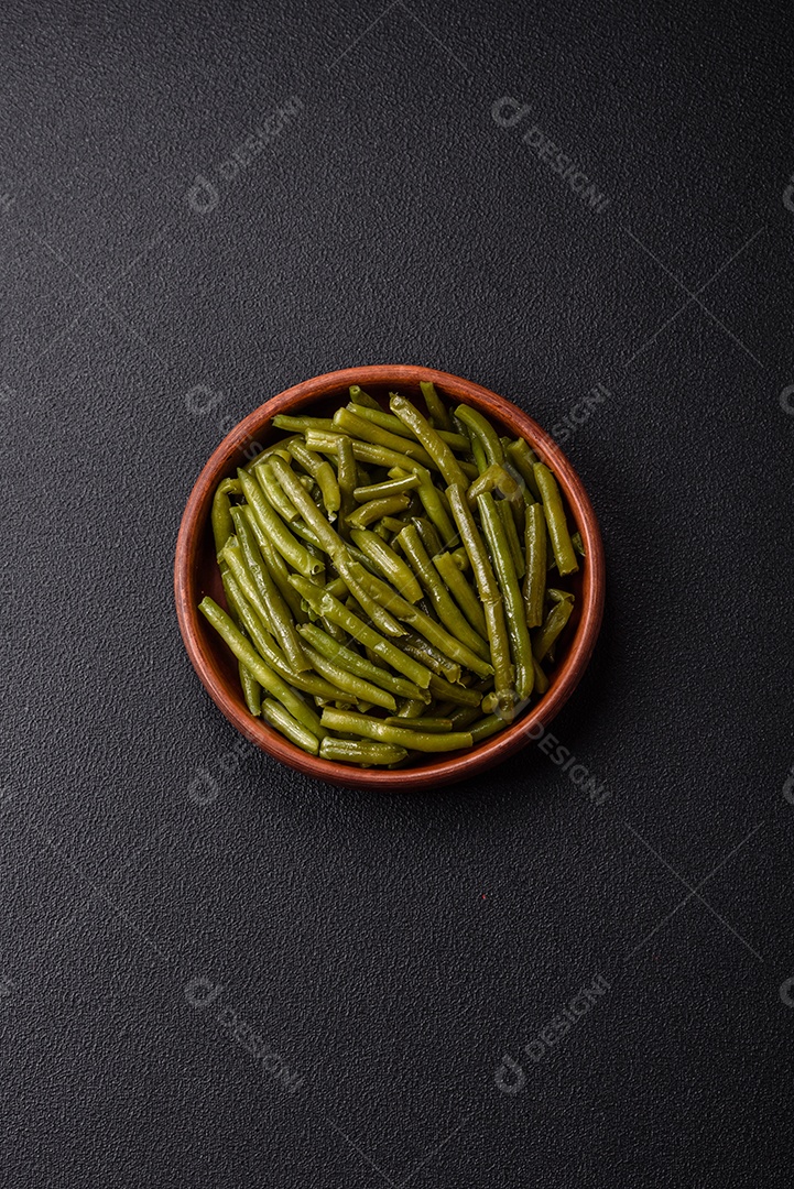 Vagens de feijão verde cozido com sal e especiarias sobre um fundo escuro de concreto