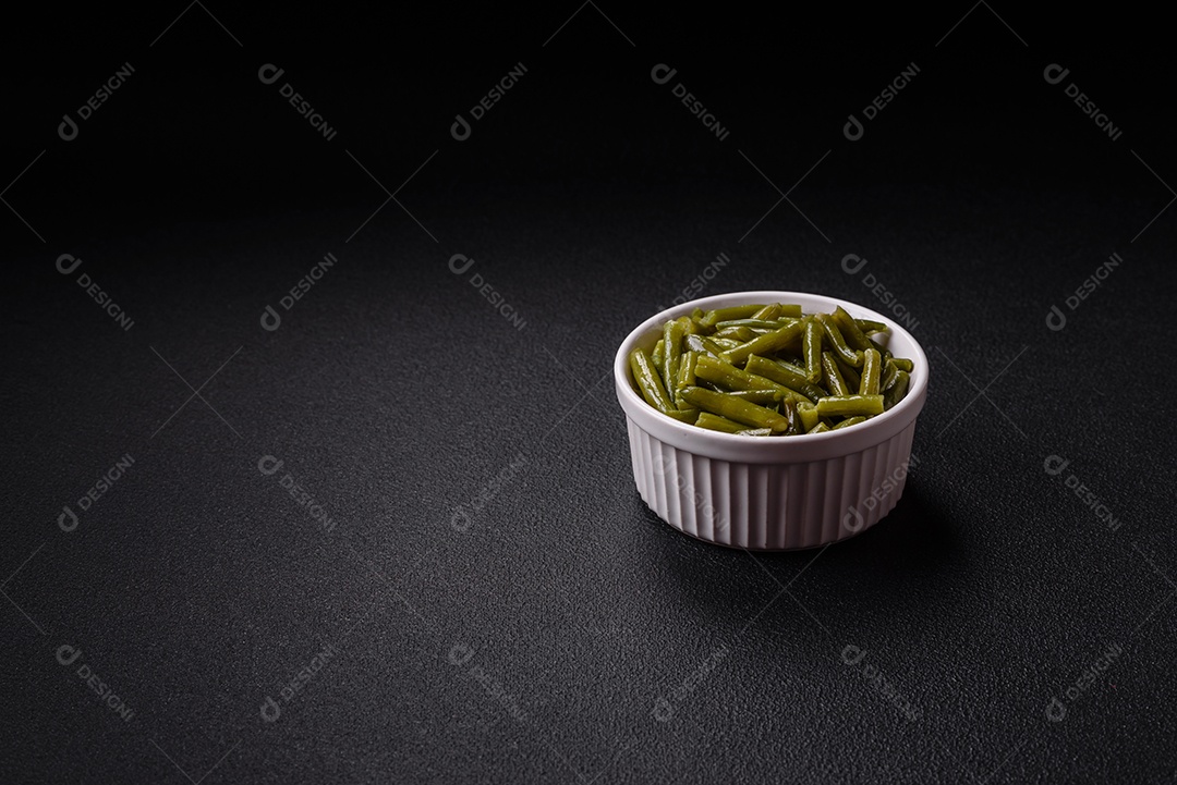 Vagens de feijão verde cozido com sal e especiarias sobre um fundo escuro de concreto