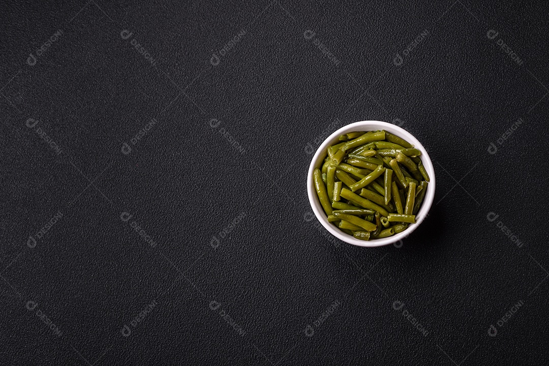 Vagens de feijão verde cozido com sal e especiarias sobre um fundo escuro de concreto