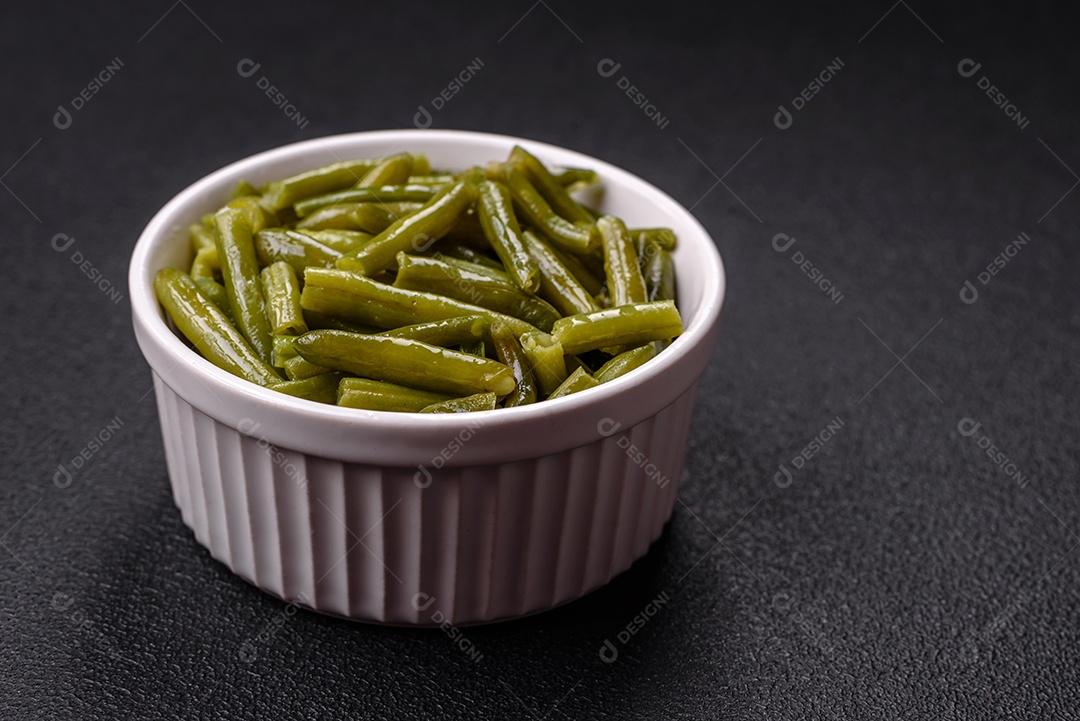 Vagens de feijão verde cozido com sal e especiarias sobre um fundo escuro de concreto
