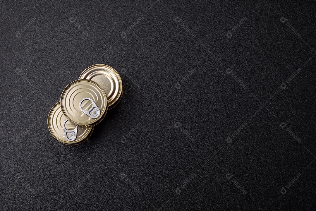 Lata redonda de metal com carne enlatada ou peixe com chave para abri-la sobre um fundo escuro de concreto