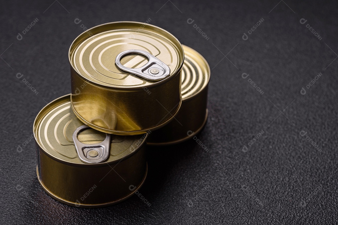 Lata redonda de metal com carne enlatada ou peixe com chave para abri-la sobre um fundo escuro de concreto