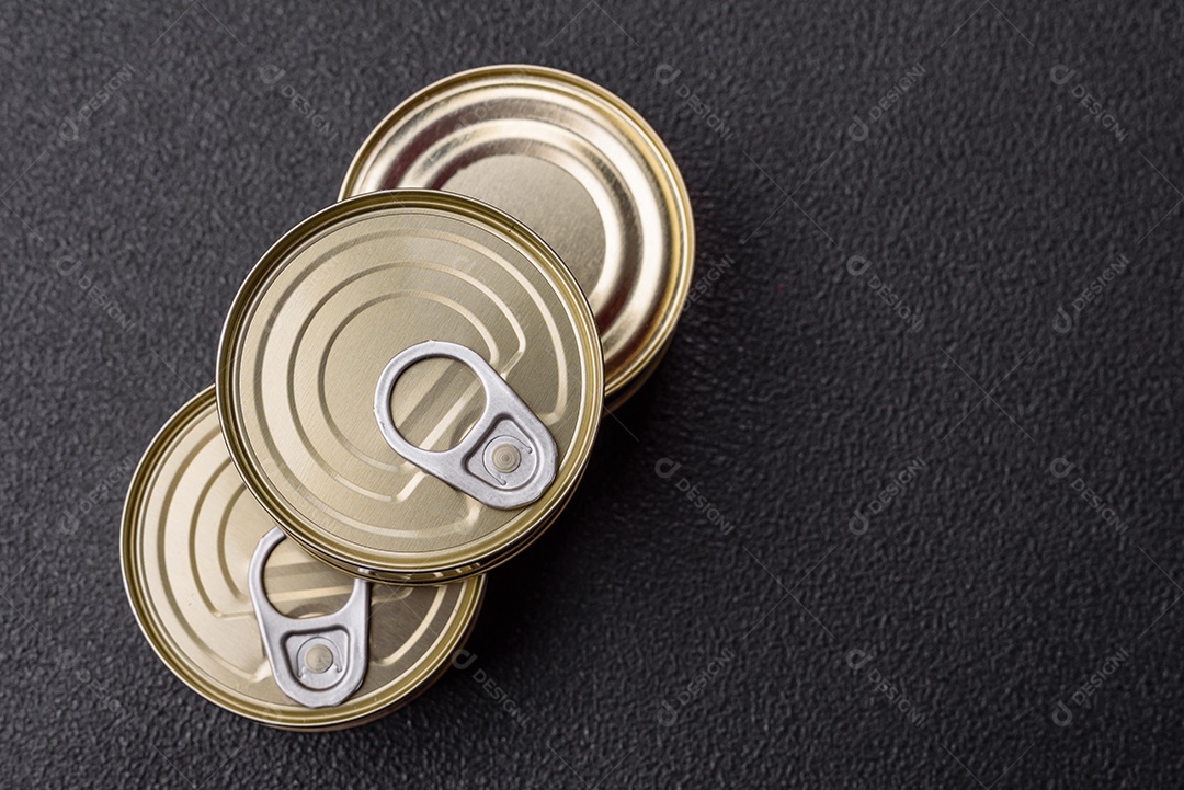 Lata redonda de metal com carne enlatada ou peixe com chave para abri-la sobre um fundo escuro de concreto