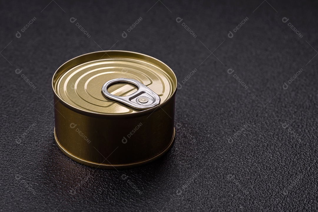 Lata redonda de metal com carne enlatada ou peixe com chave para abri-la sobre um fundo escuro de concreto