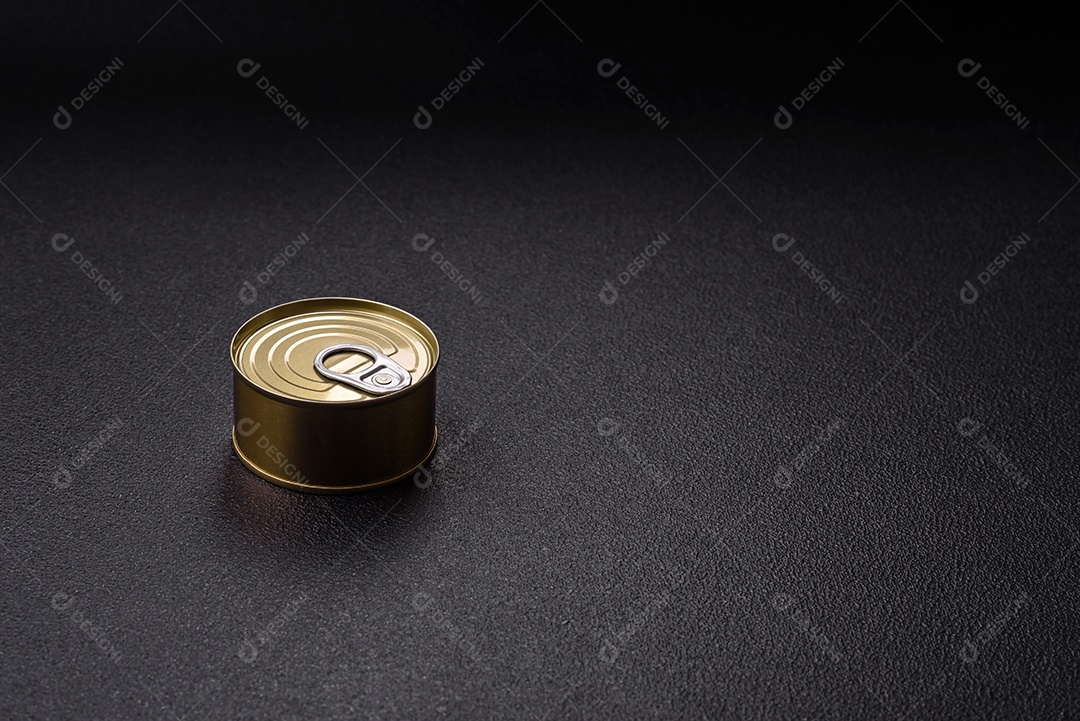 Lata redonda de metal com carne enlatada ou peixe com chave para abri-la sobre um fundo escuro de concreto