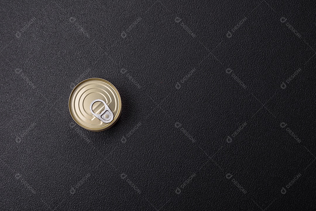 Lata redonda de metal com carne enlatada ou peixe com chave para abri-la sobre um fundo escuro de concreto
