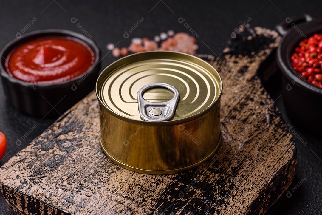 Lata redonda de metal com carne enlatada ou peixe com chave para abri-la sobre um fundo escuro de concreto