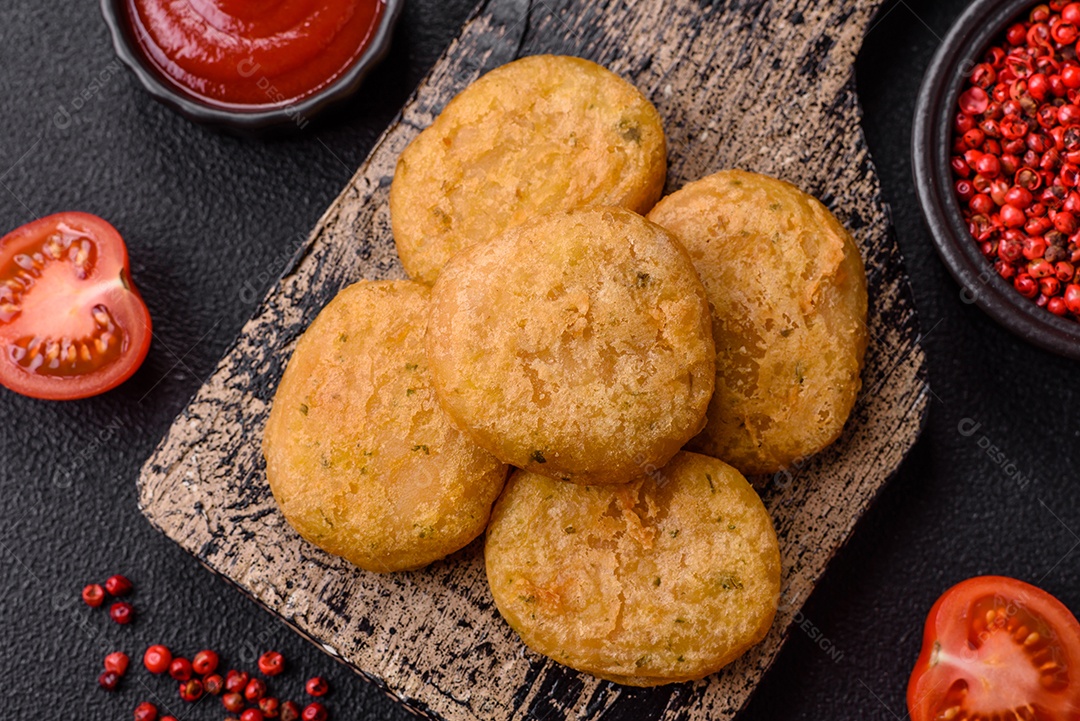 Peixe redondo ou pepitas de frango com sal e especiarias empanadas sobre um fundo escuro de concreto