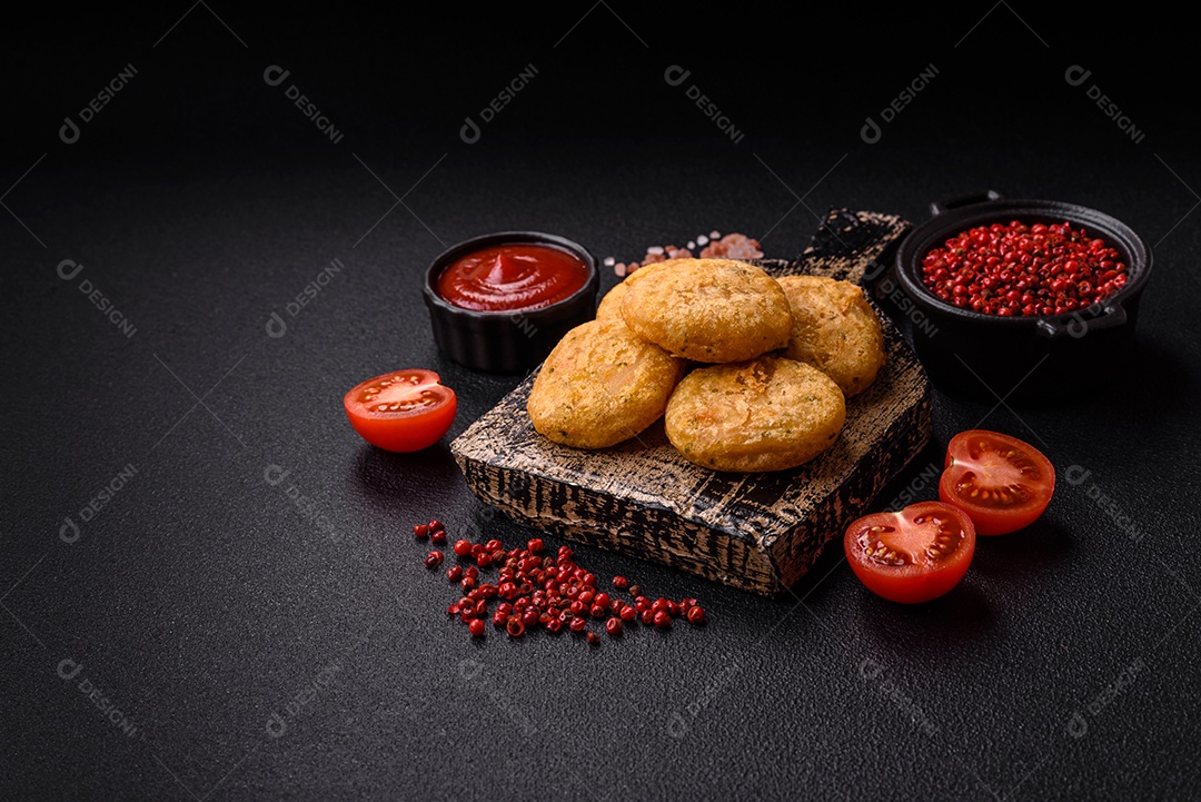Peixe redondo ou pepitas de frango com sal e especiarias empanadas sobre um fundo escuro de concreto