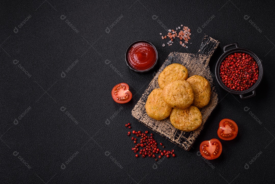 Peixe redondo ou pepitas de frango com sal e especiarias empanadas sobre um fundo escuro de concreto