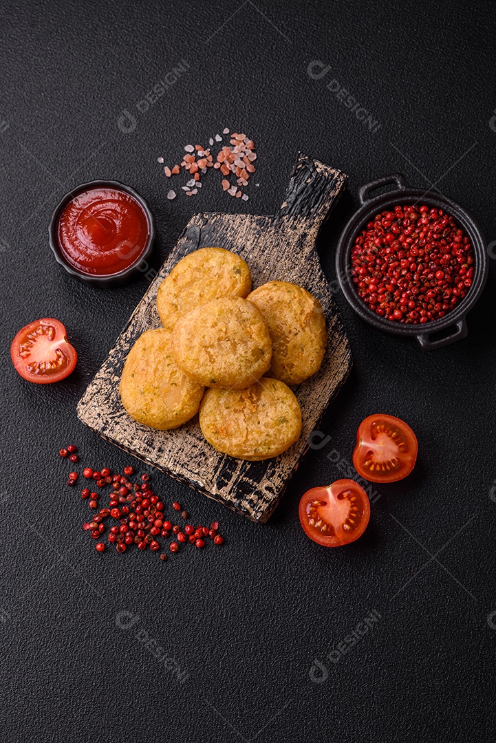 Peixe redondo ou pepitas de frango com sal e especiarias empanadas sobre um fundo escuro de concreto