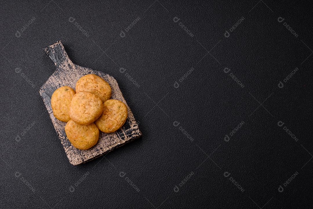Peixe redondo ou pepitas de frango com sal e especiarias empanadas sobre um fundo escuro de concreto