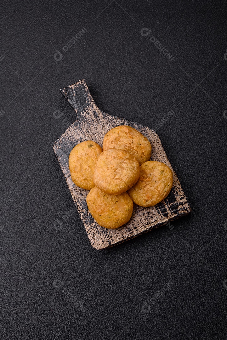 Peixe redondo ou pepitas de frango com sal e especiarias empanadas sobre um fundo escuro de concreto