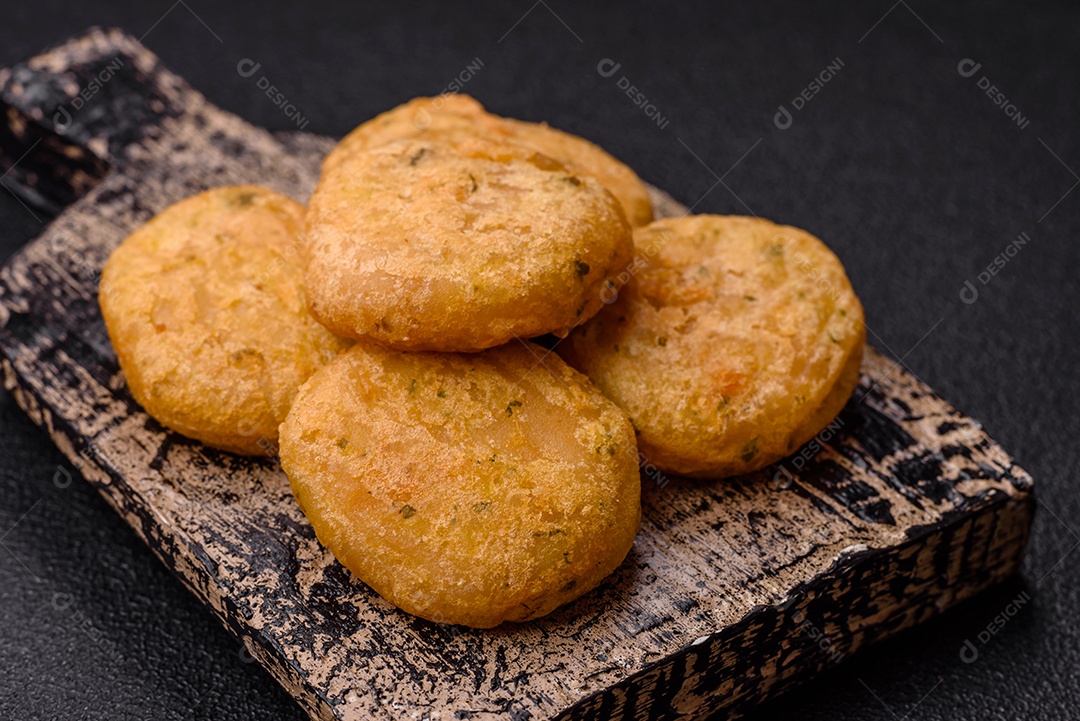 Peixe redondo ou pepitas de frango com sal e especiarias empanadas sobre um fundo escuro de concreto