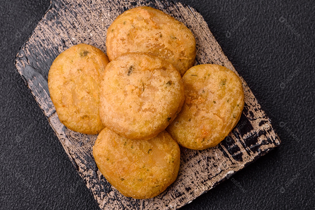 Peixe redondo ou pepitas de frango com sal e especiarias empanadas sobre um fundo escuro de concreto
