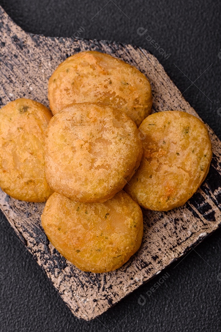 Peixe redondo ou pepitas de frango com sal e especiarias empanadas sobre um fundo escuro de concreto