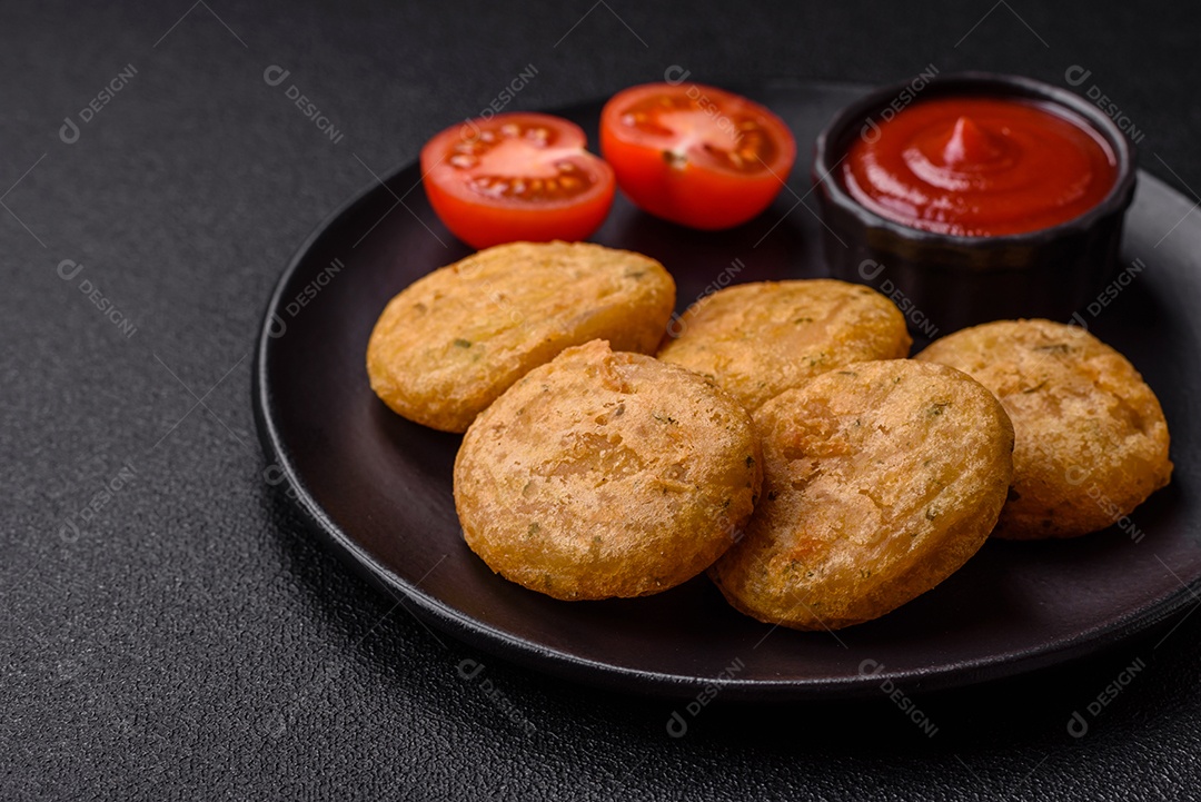Peixe redondo ou pepitas de frango com sal e especiarias empanadas sobre um fundo escuro de concreto