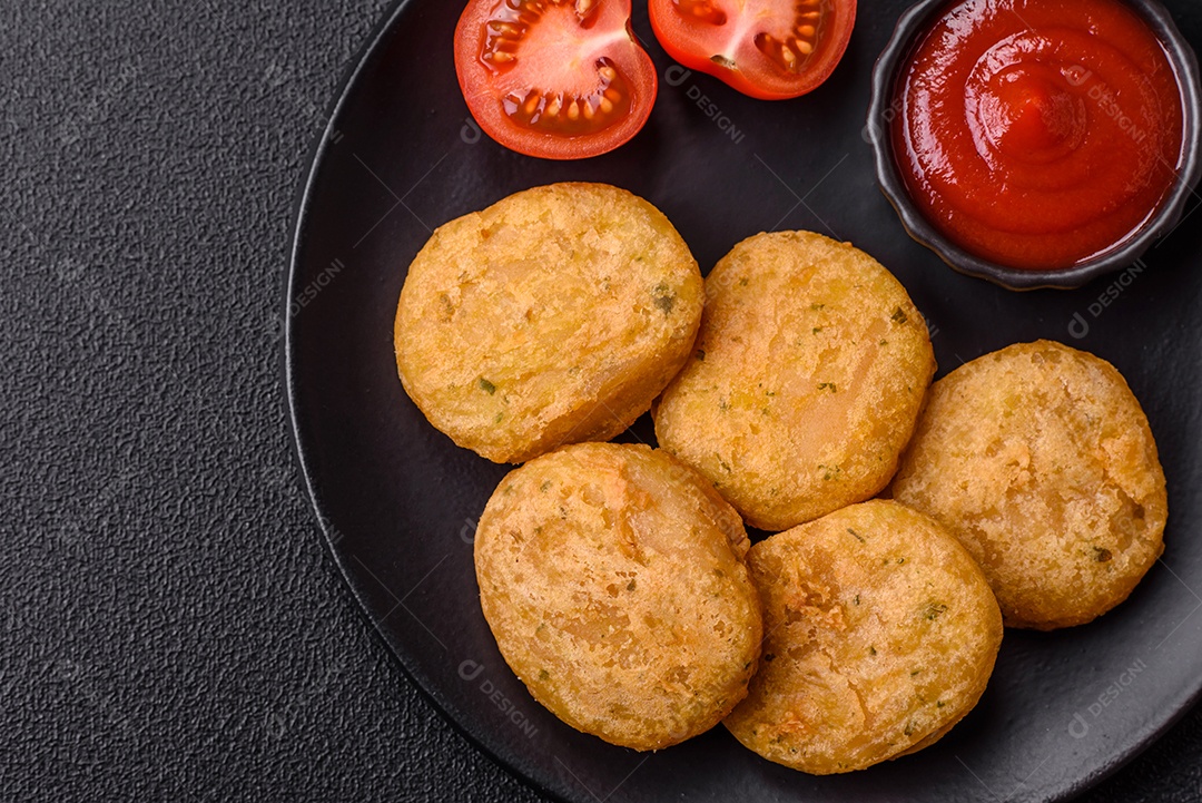 Peixe redondo ou pepitas de frango com sal e especiarias empanadas sobre um fundo escuro de concreto