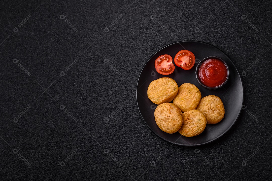 Peixe redondo ou pepitas de frango com sal e especiarias empanadas sobre um fundo escuro de concreto