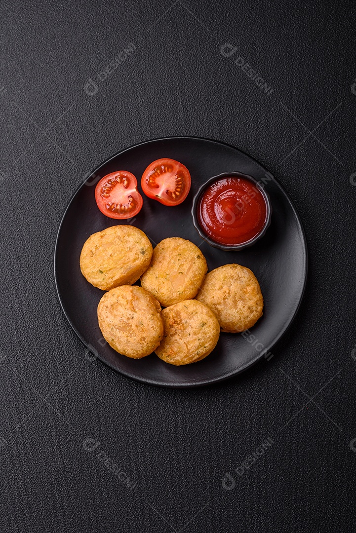 Peixe redondo ou pepitas de frango com sal e especiarias empanadas sobre um fundo escuro de concreto