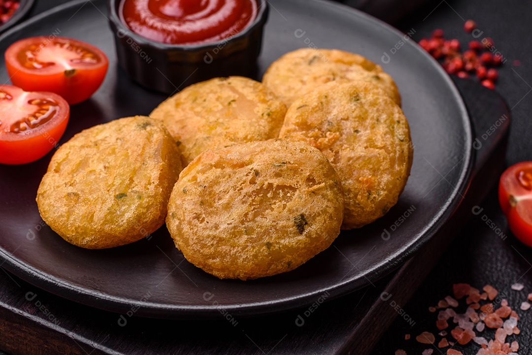 Peixe redondo ou pepitas de frango com sal e especiarias empanadas sobre um fundo escuro de concreto